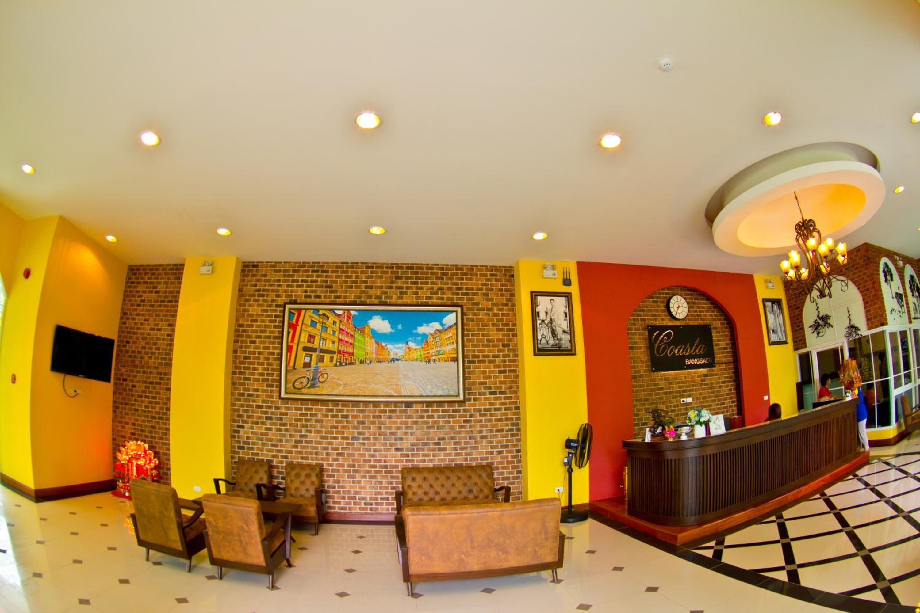 A lobby with a brick wall, a reception desk, and a seating area with chairs and a sofa.