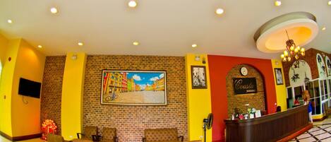 A lobby with a brick wall, a reception desk, and a seating area with chairs and a sofa.