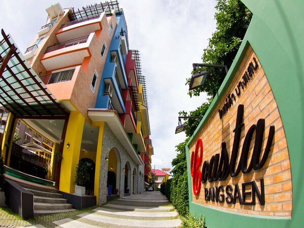 A multi-story building with a colorful facade, a sign for "Casta Bangsaen," and a staircase leading to the entrance. - Coasta Bangsaen (Chonburi)