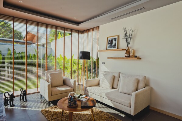 A modern living room with a sofa, armchair, and coffee table. - Villa Sunpao (Choeng Thale)