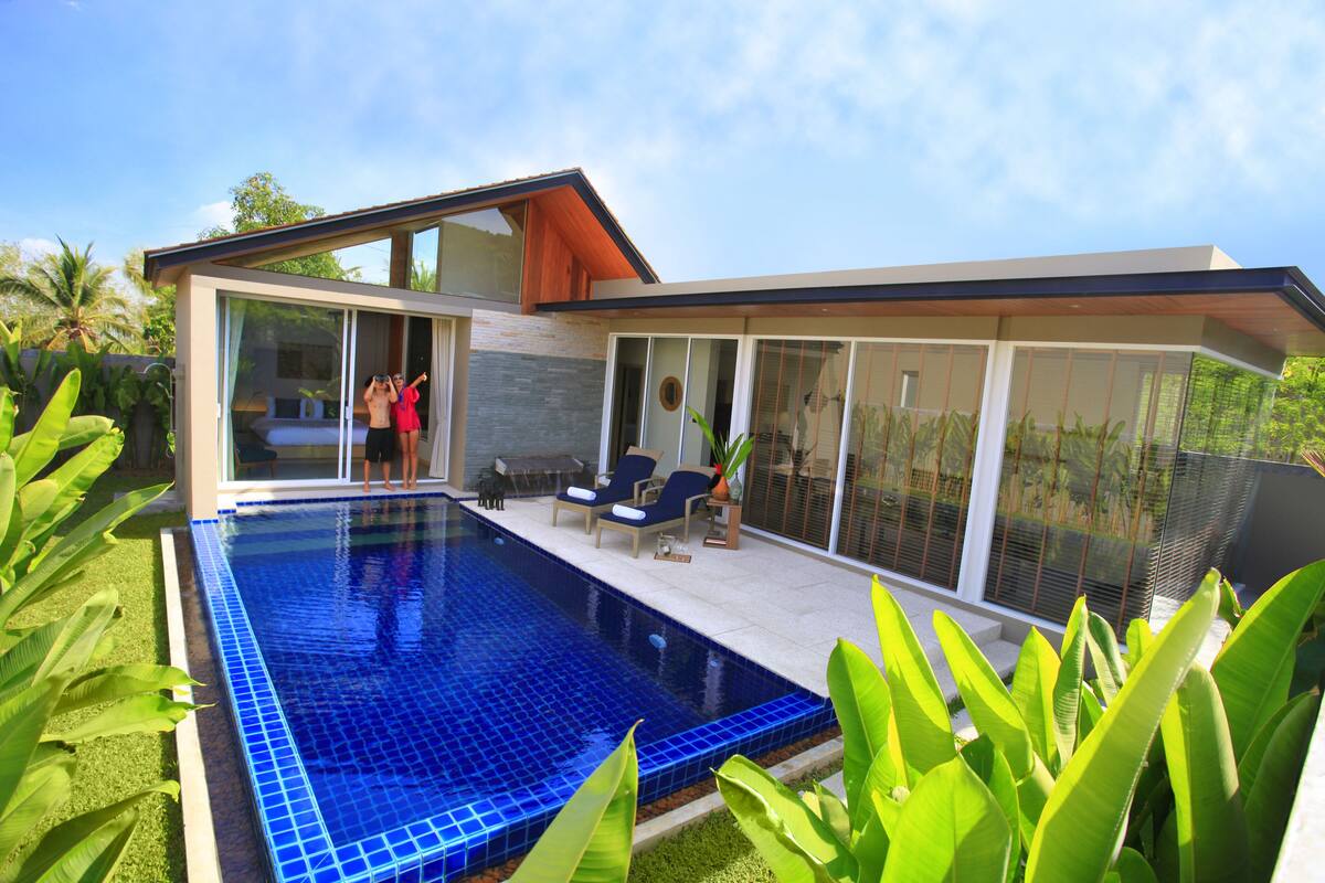 A modern house with a swimming pool, glass doors, and a patio area.