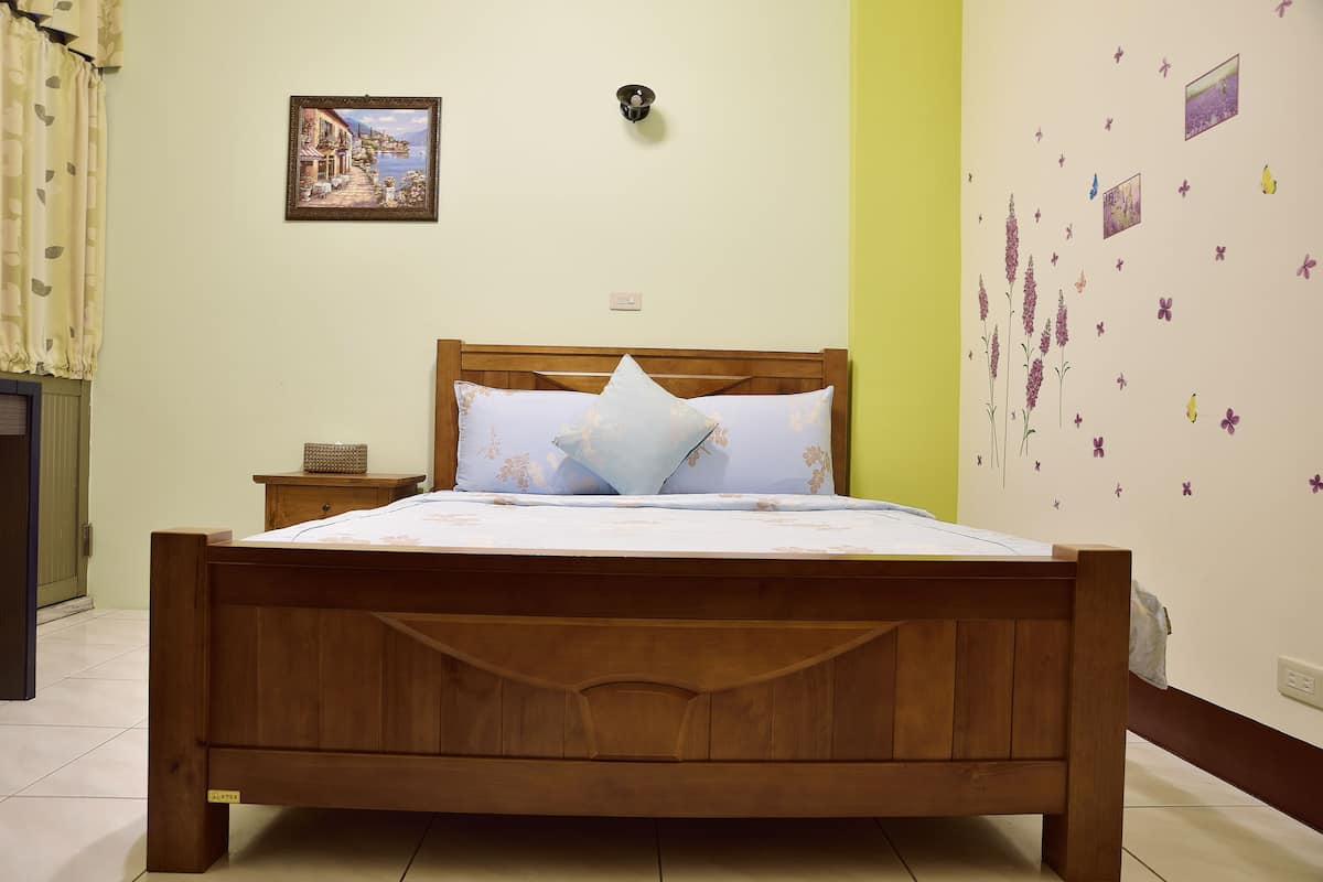 Un lit en bois avec une tête de lit, une table de chevet et un tableau accroché au mur.