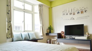 A bedroom with a bed, a TV, a desk, and a window with curtains. - Feng's B&B (Hualien City)