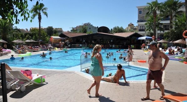 A swimming pool area with multiple pools, sun loungers, and umbrellas.