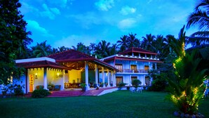 A two-story building with a red-tiled roof, a covered patio, and a well-maintained lawn. - Waterside Bentota (Bentota)