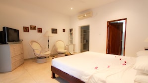 A bedroom with a bed, a television, a chair, a wardrobe, and a door. - Waterside Bentota (Bentota)