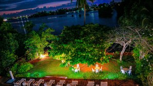 A nighttime view of a lakeside area with outdoor seating and lounge chairs. - Waterside Bentota (Bentota)