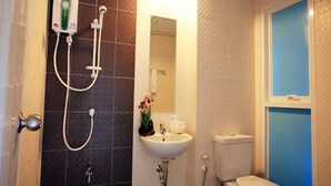 A bathroom with a shower, sink, toilet, and a window. - Similan Mansion (Chonburi)