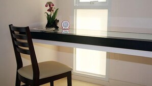 A room with a glass desk, a wooden chair, a small potted plant, and a wall-mounted clock. - Similan Mansion (Chonburi)
