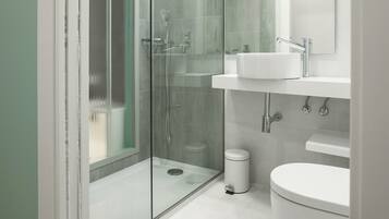 A modern bathroom with a glass-enclosed shower, a white sink, and a toilet.