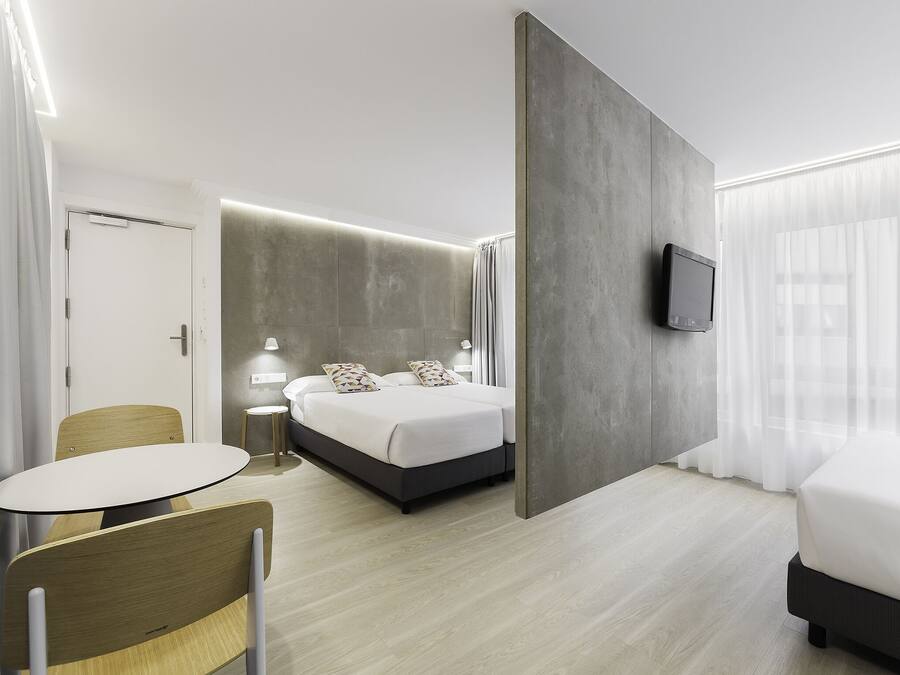 A modern hotel room with a bed, a small table, and a chair.
