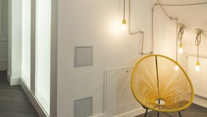 A modern interior with a reception desk, a yellow chair, and exposed ductwork on the ceiling. - Hotel Mar del Plata (A Coruña)