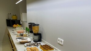 Un bufé con diversas opciones de comida, incluyendo pasteles, frutas y bebidas.
