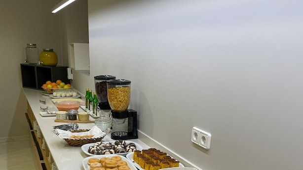 Un bufé con diversas opciones de comida, incluyendo pasteles, frutas y bebidas.