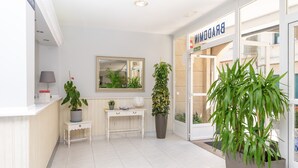 Un área de recepción con una consola blanca, un espejo, una planta en maceta, un escritorio y una puerta con la leyenda 'BRADFORD'.