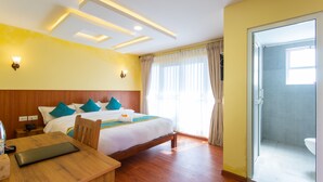 A hotel room with a bed, bedside table, and a bathroom with a shower and toilet. - Naikap Village Resort (Chandragiri)