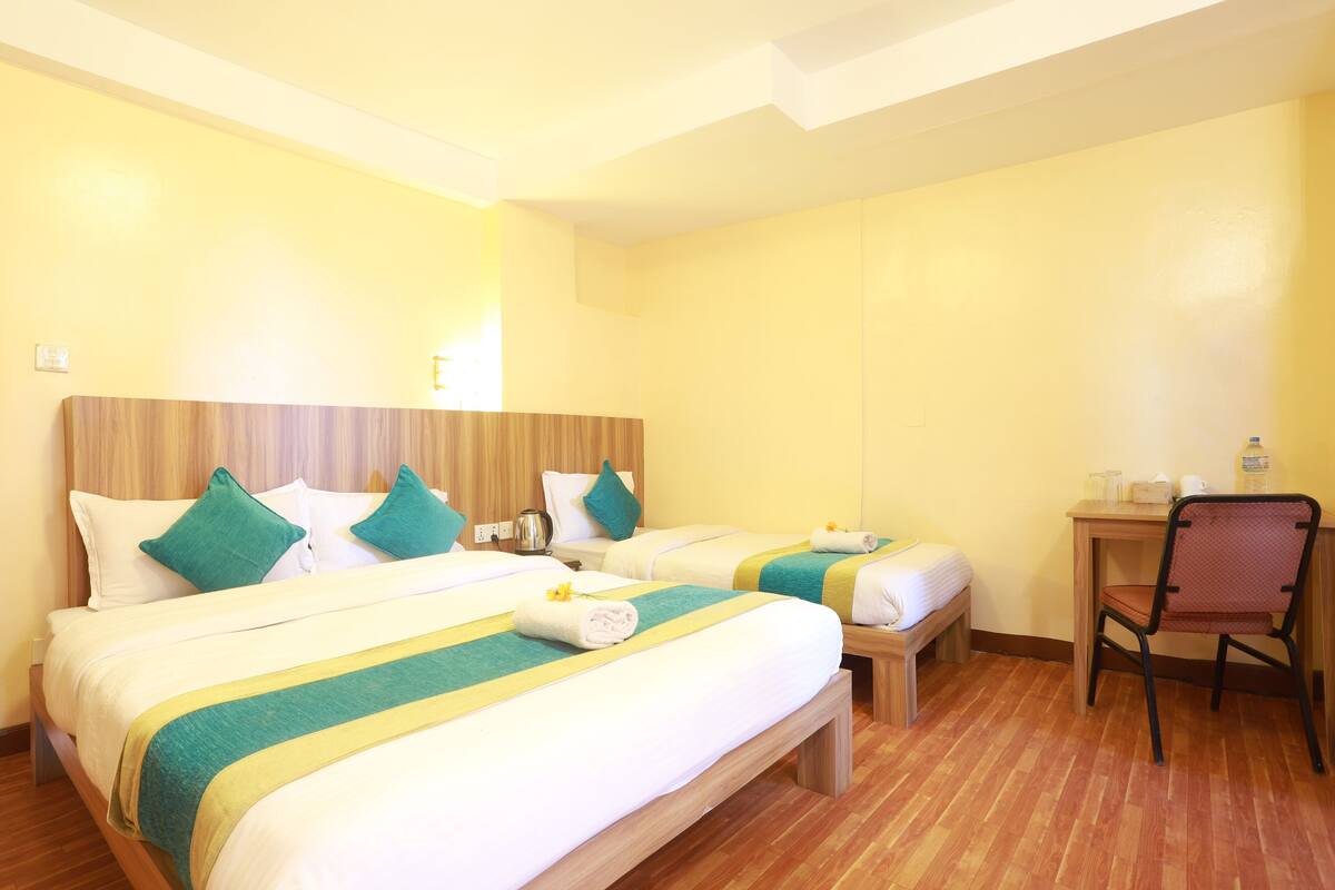 A hotel room with two beds, a desk, and a chair.
