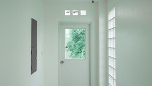 Eine weiße Tür mit kleinem Fenster, Klingel und einem an der Wand montierten Gegensprechanlage.