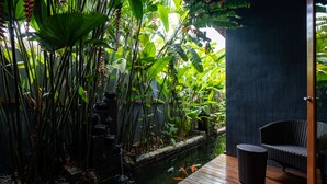 A serene indoor garden with a koi pond, lush greenery, and a wooden deck with a wicker chair. - Ipoh Bali Hotel (Ipoh)