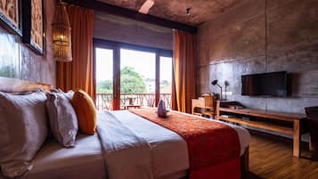 A hotel room with a large bed, wooden furniture, a television, and a balcony with a view.