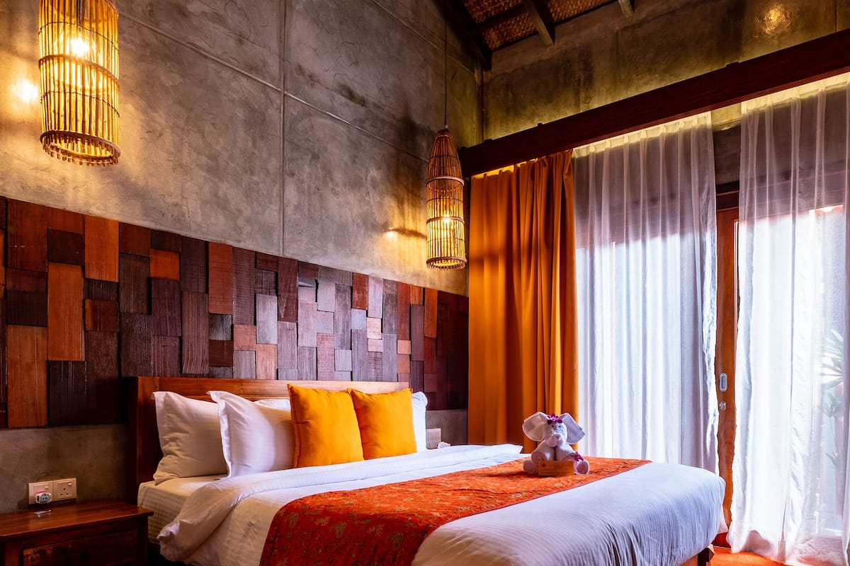 A large bed with a wooden headboard, a nightstand, and a plush teddy bear.