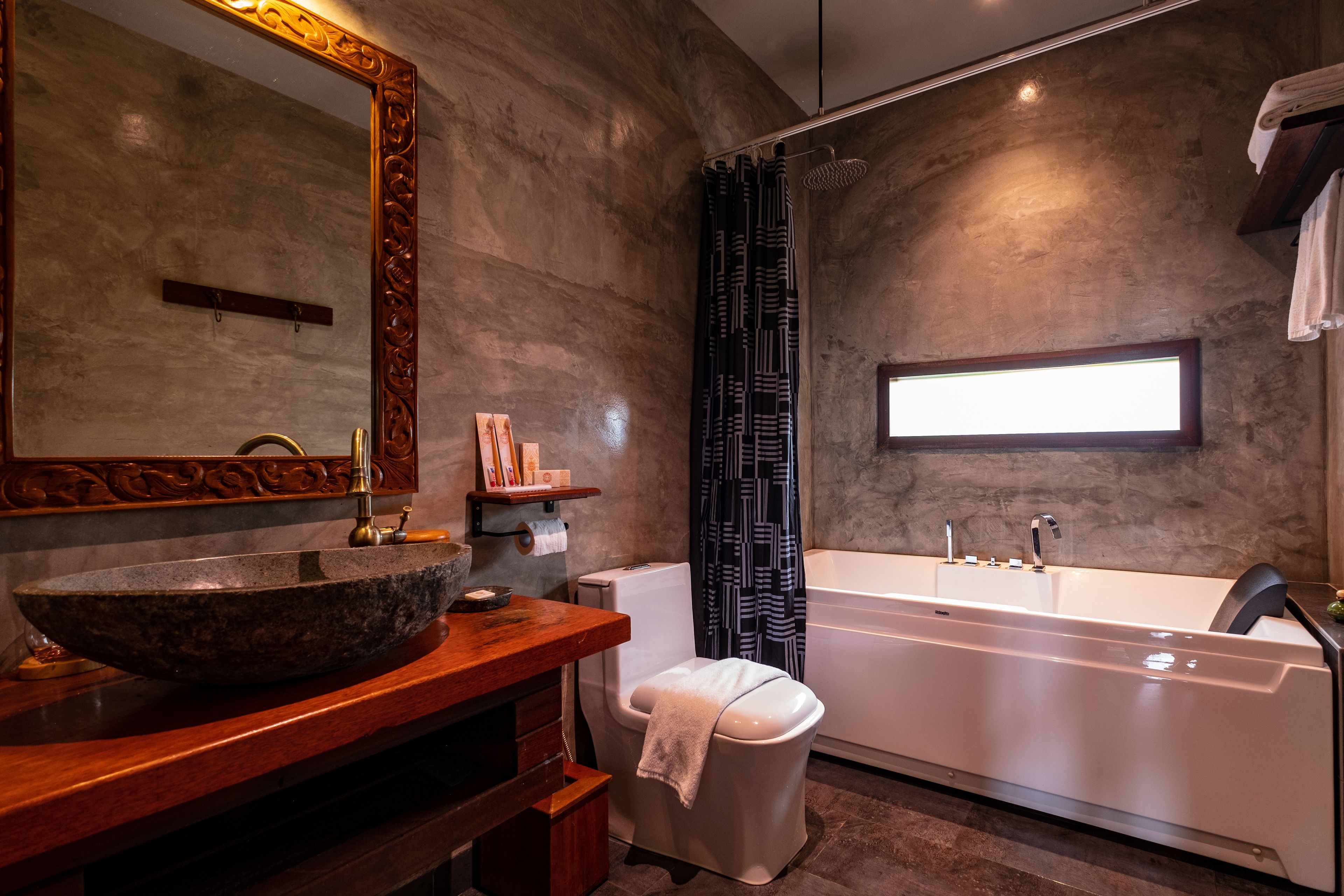 A modern bathroom with a large stone sink, a freestanding toilet, and a walk-in bathtub.