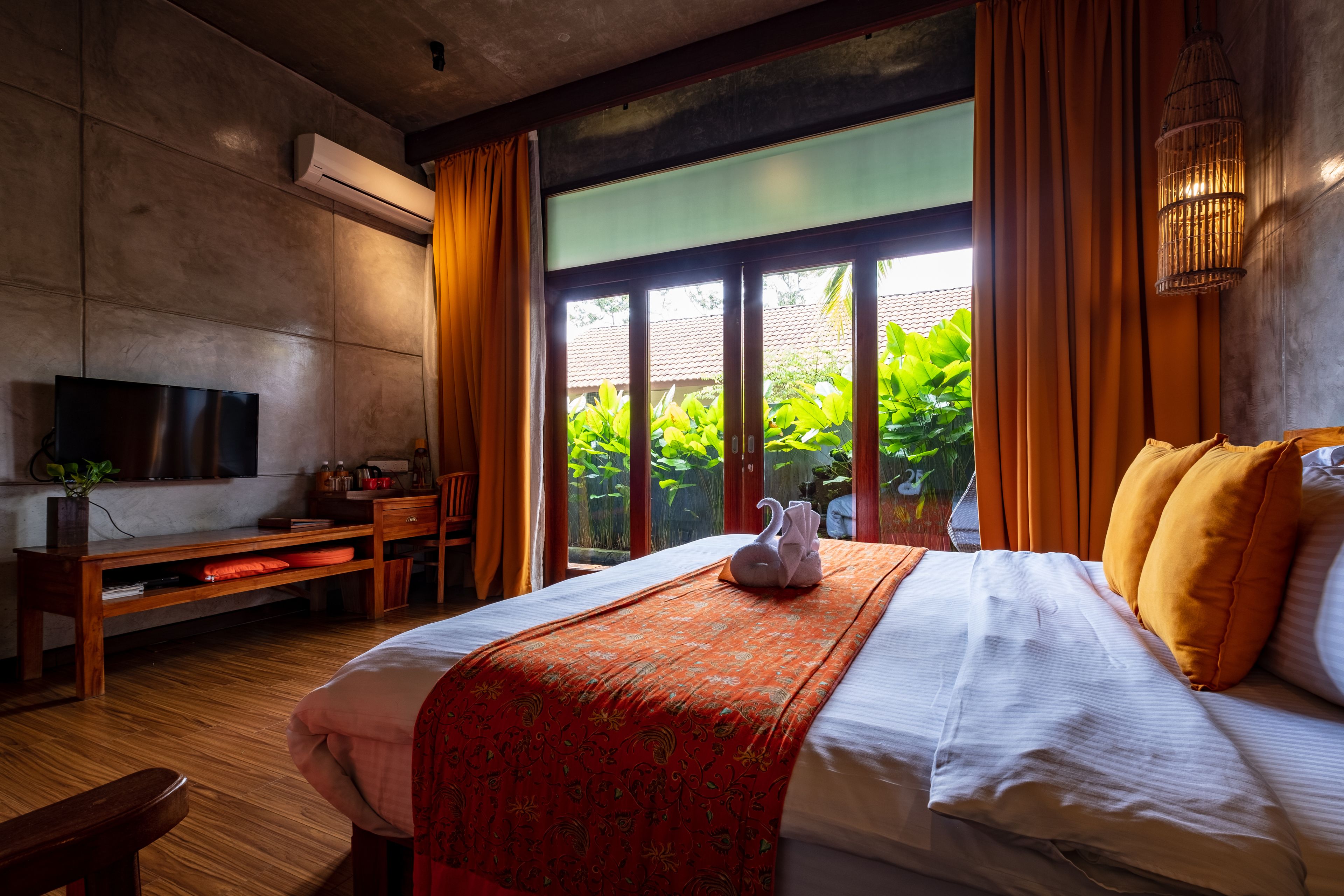 Habitación de hotel con cama, televisión, escritorio y vista a zonas verdes.