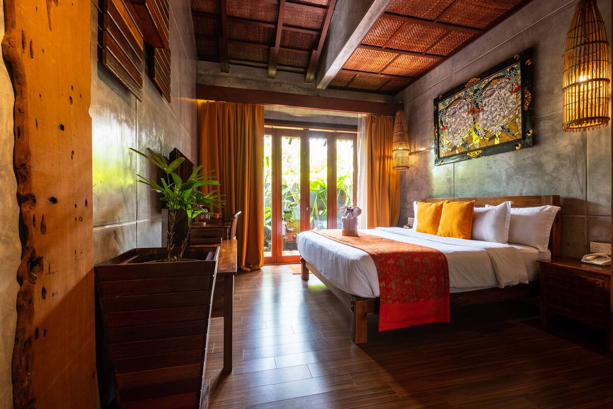 A wooden staircase leading to a room with a bed, a nightstand, and a wall-mounted lamp.
