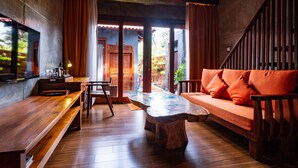 A cozy room with a wooden bench, a sofa with orange cushions, and a large table. - Ipoh Bali Hotel (Ipoh)