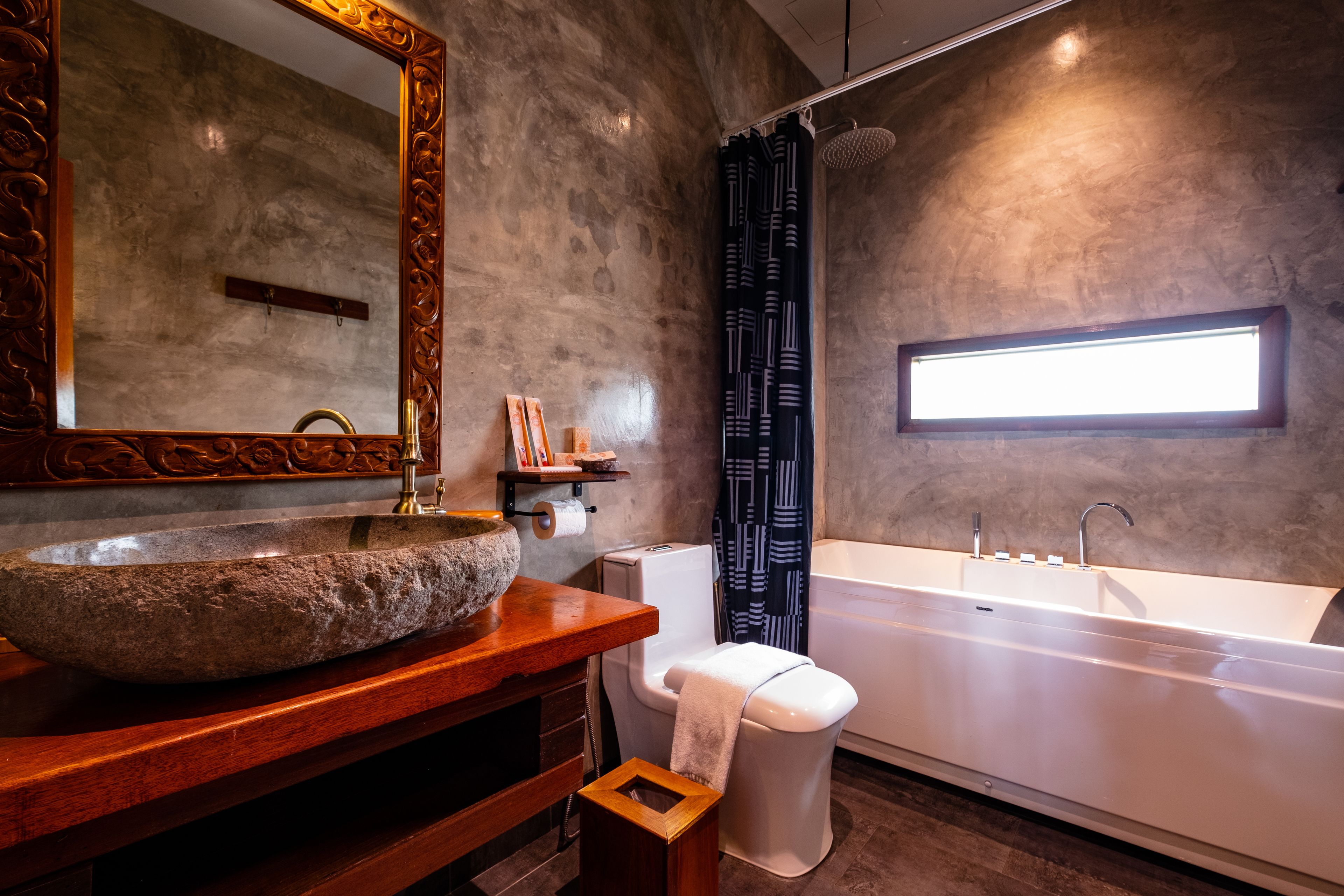 A bathroom with a stone sink, a toilet, and a bathtub.