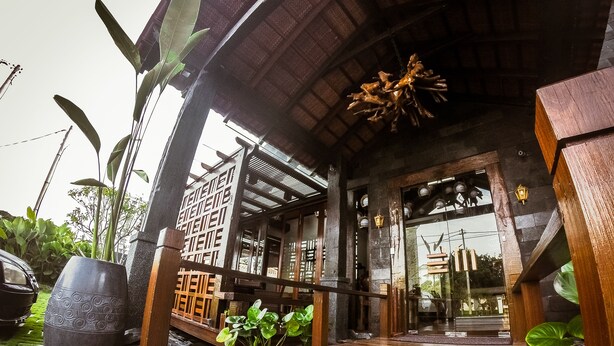 A traditional wooden structure with a thatched roof, a wooden porch, and a stone wall. - Ipoh Bali Hotel (Ipoh)