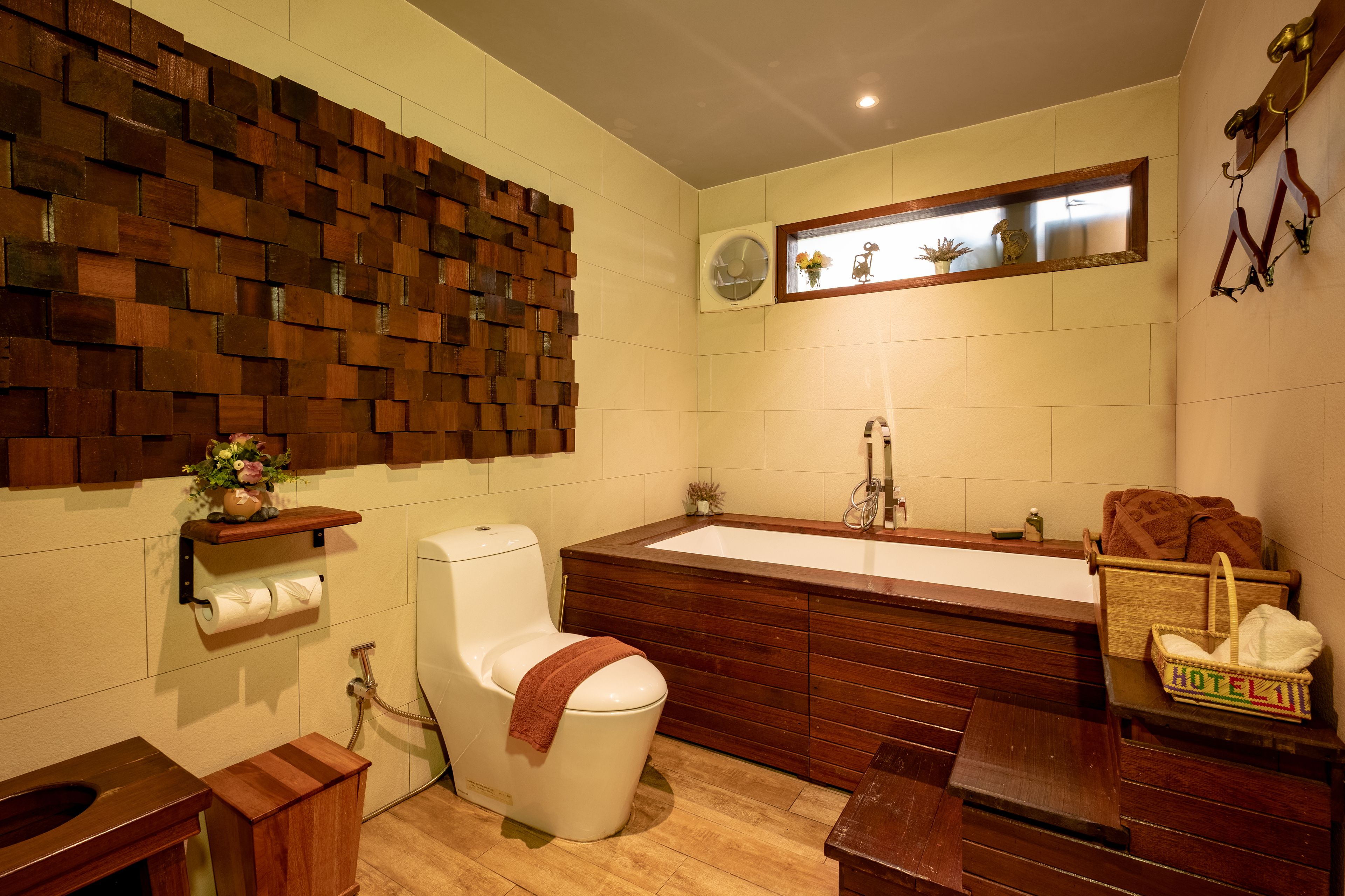 A bathroom with a wooden wall panel, a toilet, a sink, and a wooden bench.