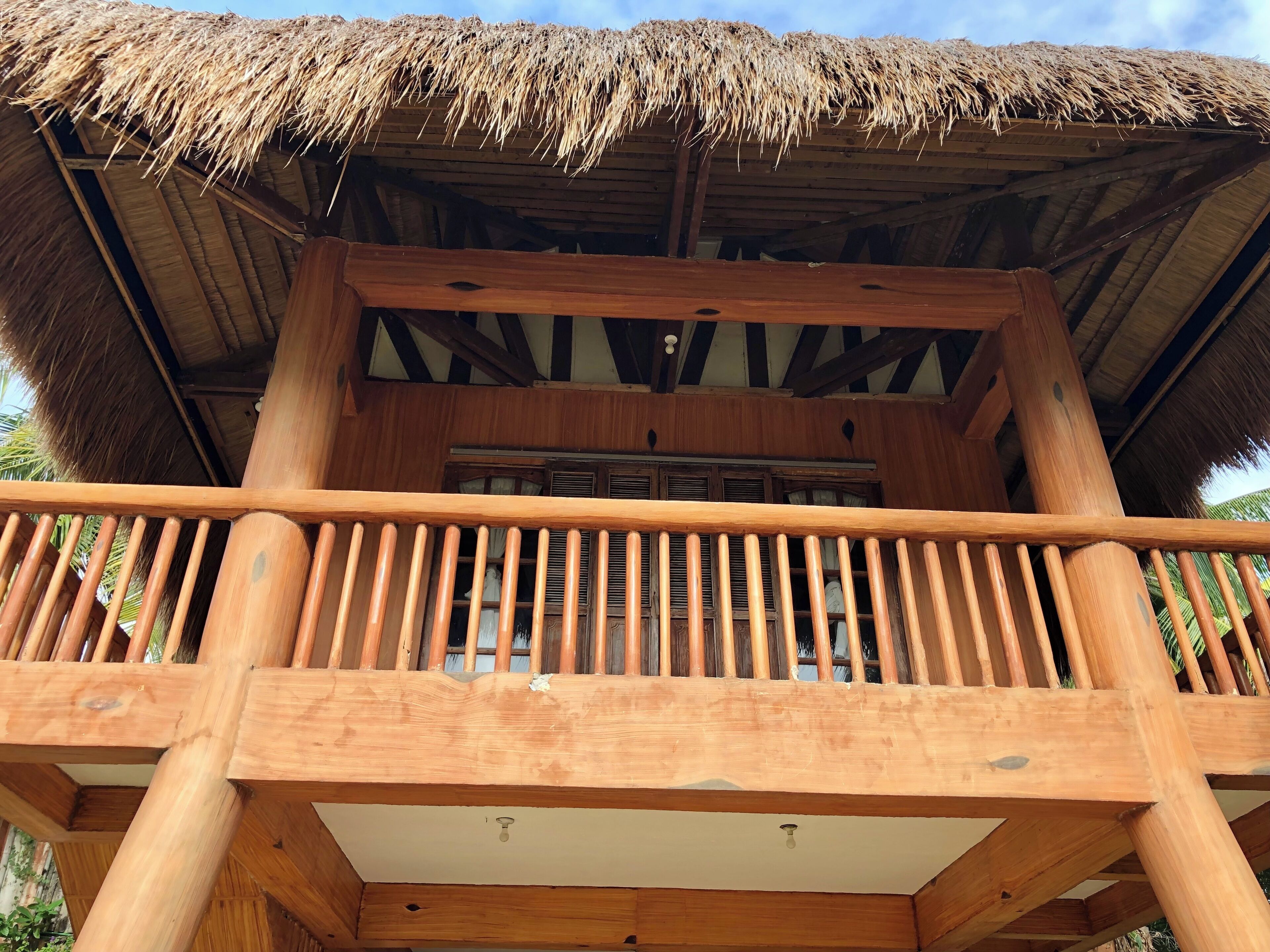 Ein Holzbalkon mit einem Reetdach, Holzgeländern und Blick auf die Umgebung.