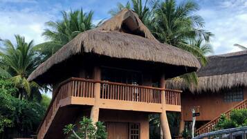 Guests can enjoy a balcony with outdoor seating amidst lush greenery and a nearby pool.