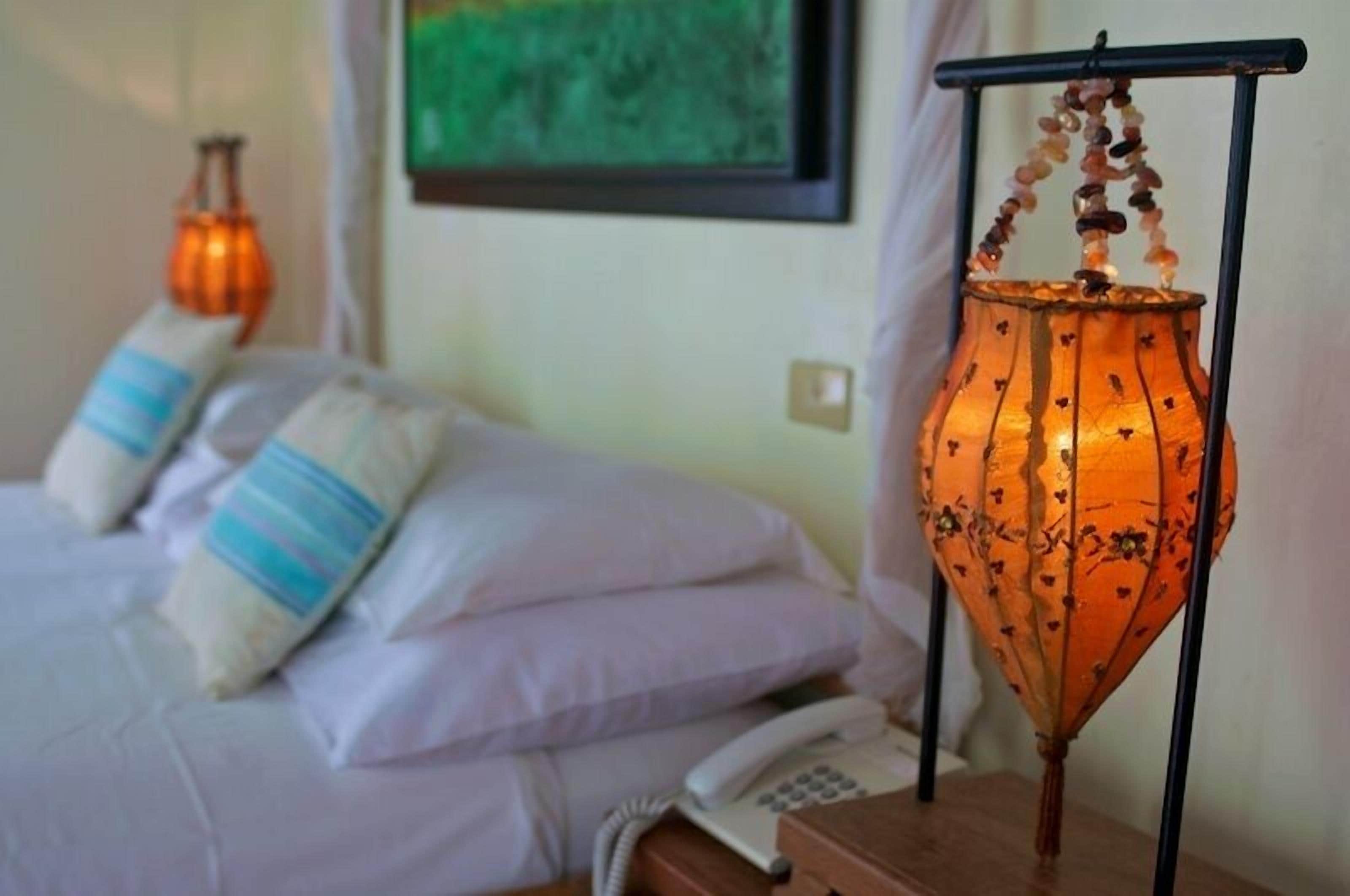 A bed with pillows, a bedside phone, and a hanging lantern.