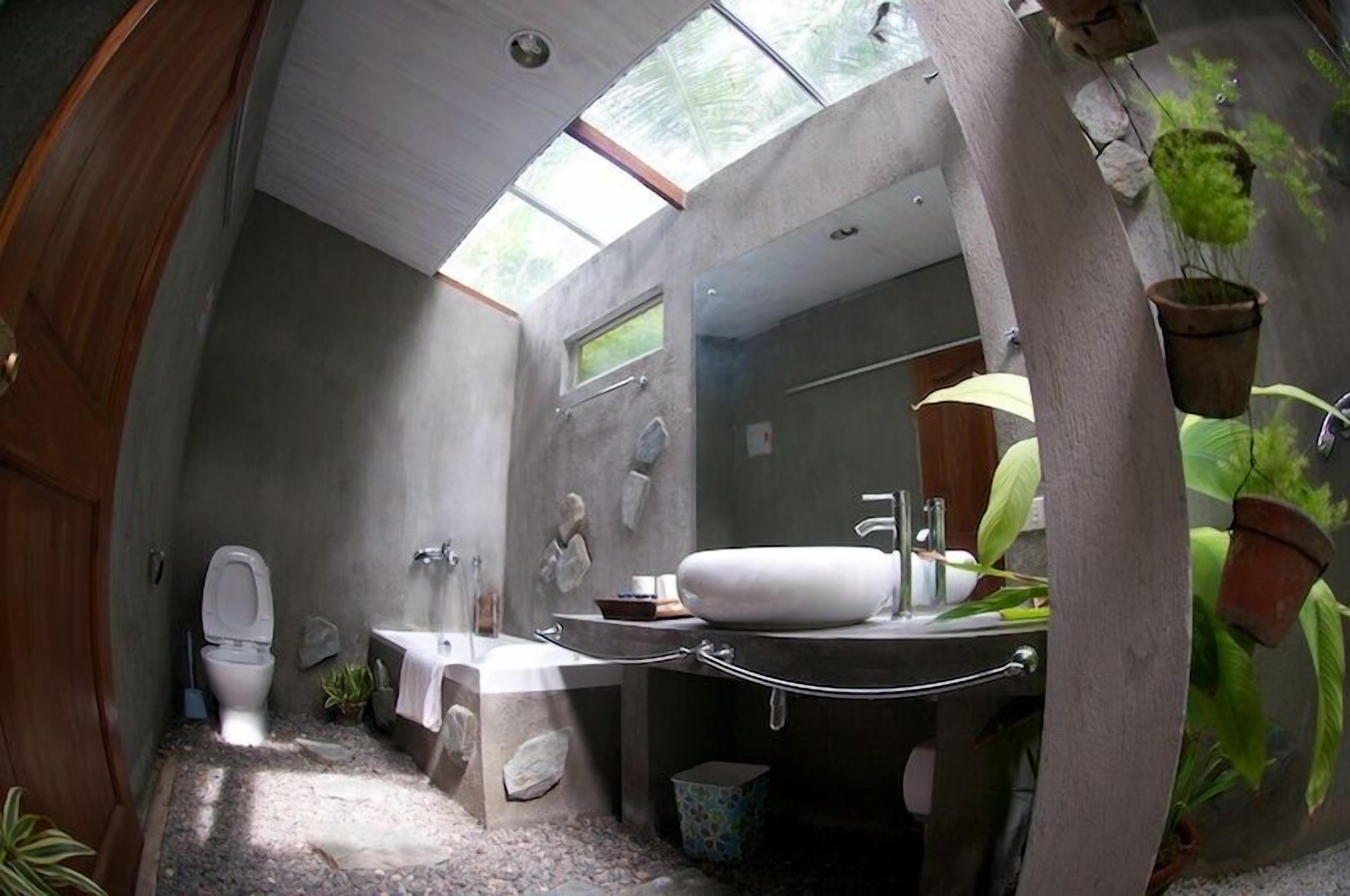Une salle de bain avec un puits de lumière, des toilettes, un lavabo et une baignoire.