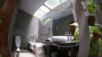 Une salle de bain avec un puits de lumière, des toilettes, un lavabo et une baignoire.