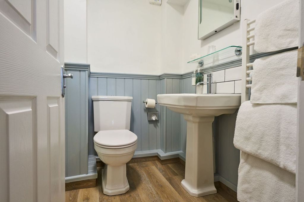 Un baño con inodoro, lavamanos y perchero para toallas.