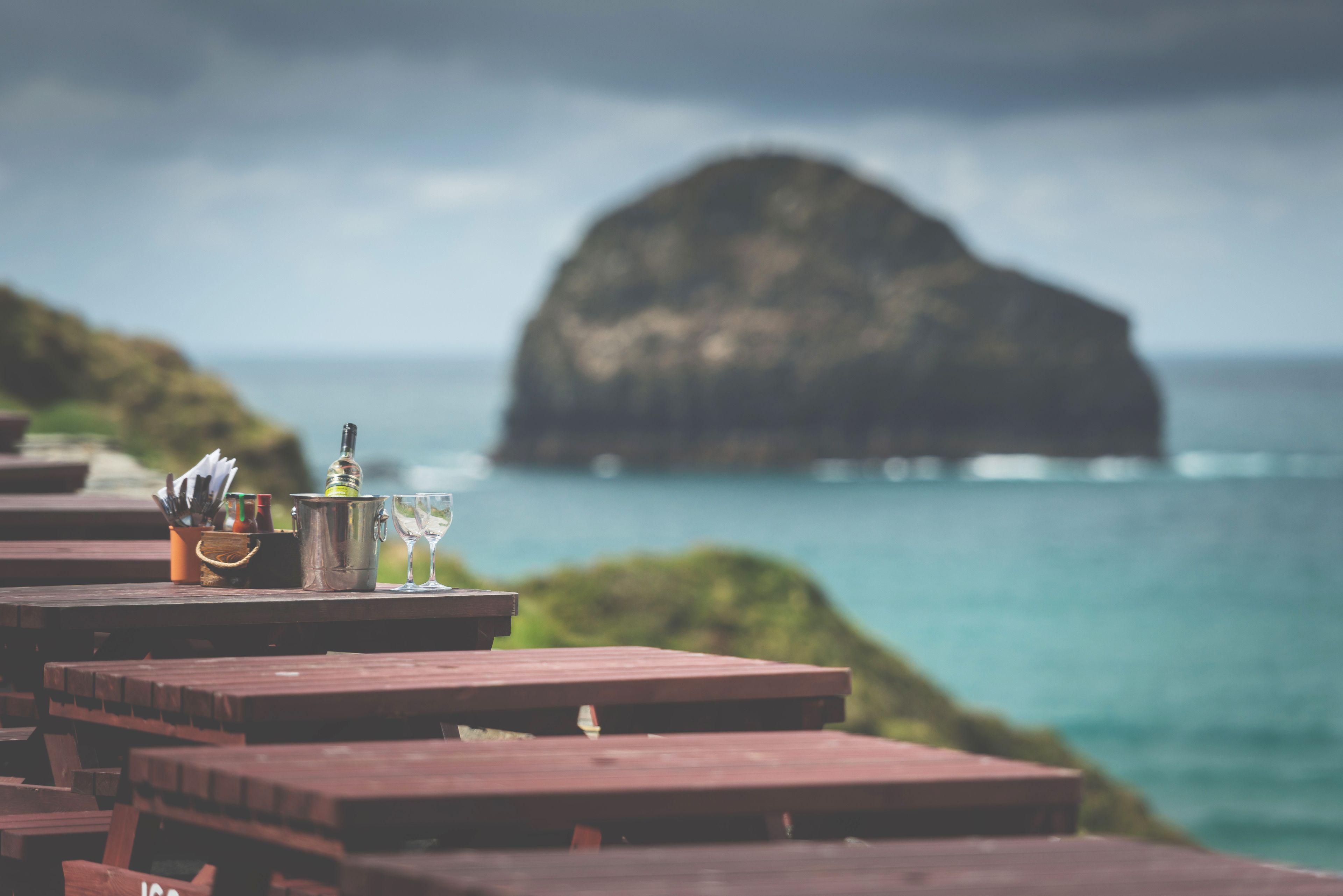A wooden table with a metal bucket, a bottle, and a glass.