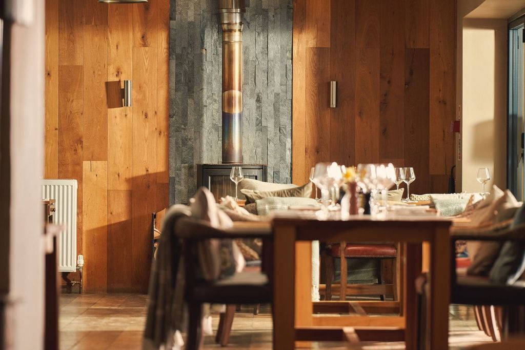 Un comedor con una mesa de madera dispuesta para una comida, una chimenea de piedra y vistas al exterior.