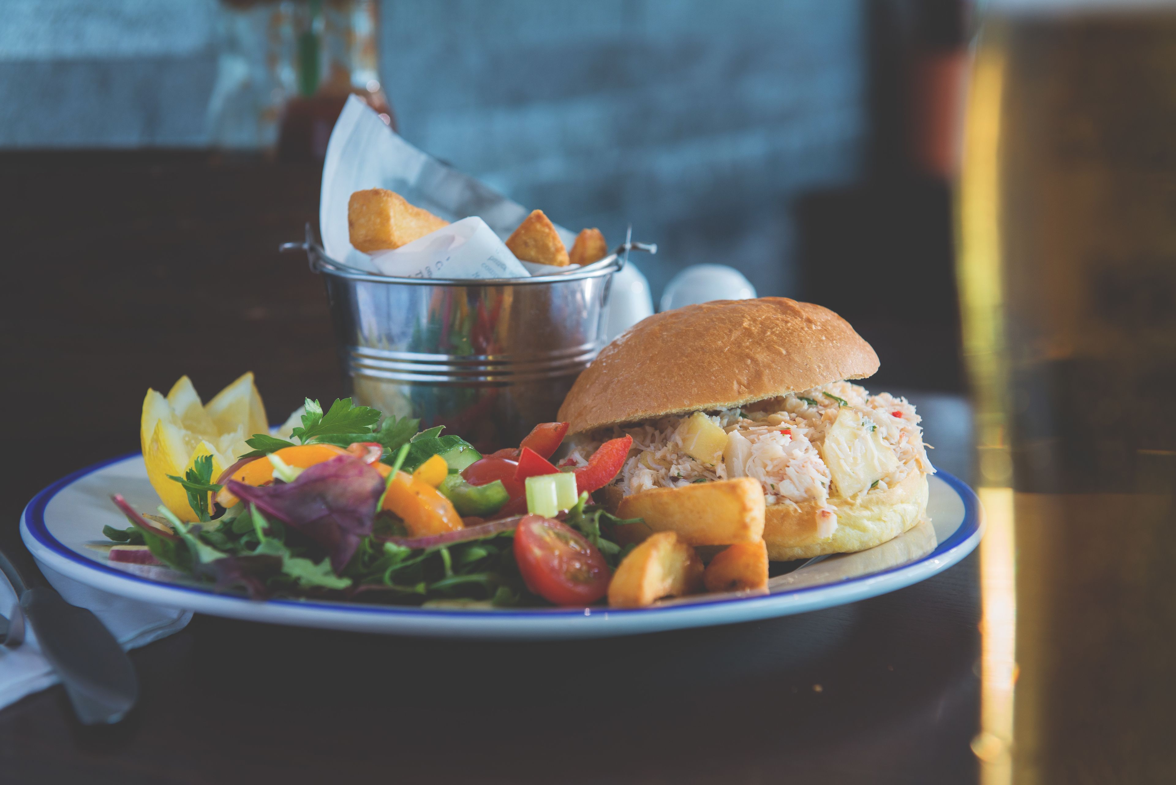 A plate with a sandwich, salad, and potato wedges.