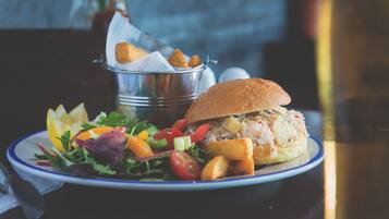 A plate with a sandwich, salad, and potato wedges.