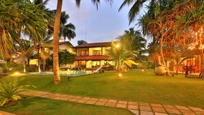 A two-story house with a swimming pool, surrounded by palm trees and a well-maintained lawn. - Sea Rock Villa (Induruwa)