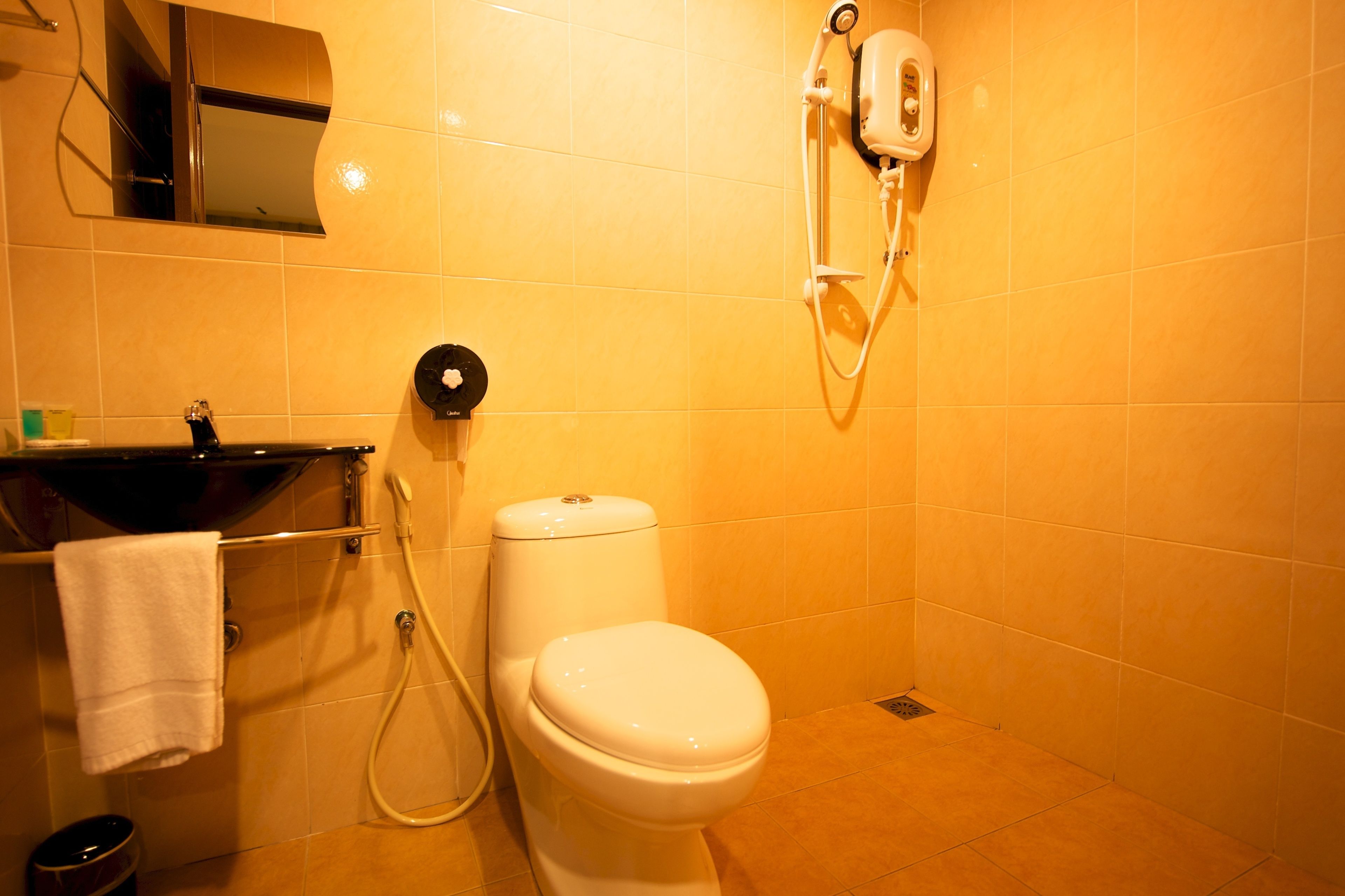 A bathroom with a toilet, a sink, a towel, and a shower unit.