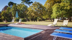 A wooden deck with a swimming pool, lounge chairs, and a grassy area with trees. - Palazzo Gatteschi (Poppi)