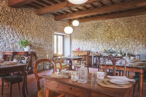 Un coin repas rustique avec des murs en pierre, des meubles en bois et une cheminée en pierre.