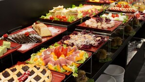 Ein Buffet mit verschiedenen Speisen, darunter Fleisch, Käse und Desserts.