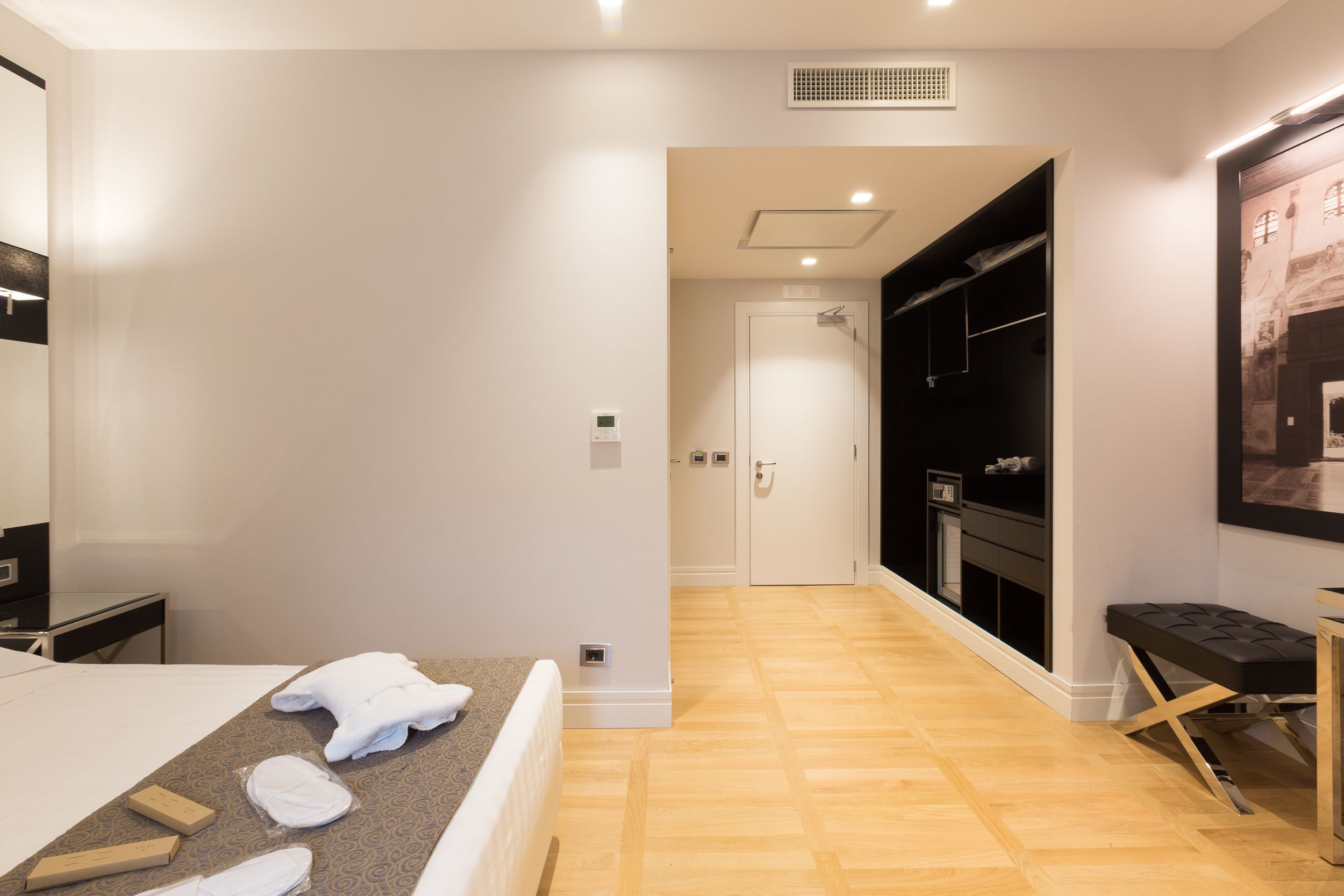 Una habitación de hotel con una cama, un escritorio, un banco y un armario.