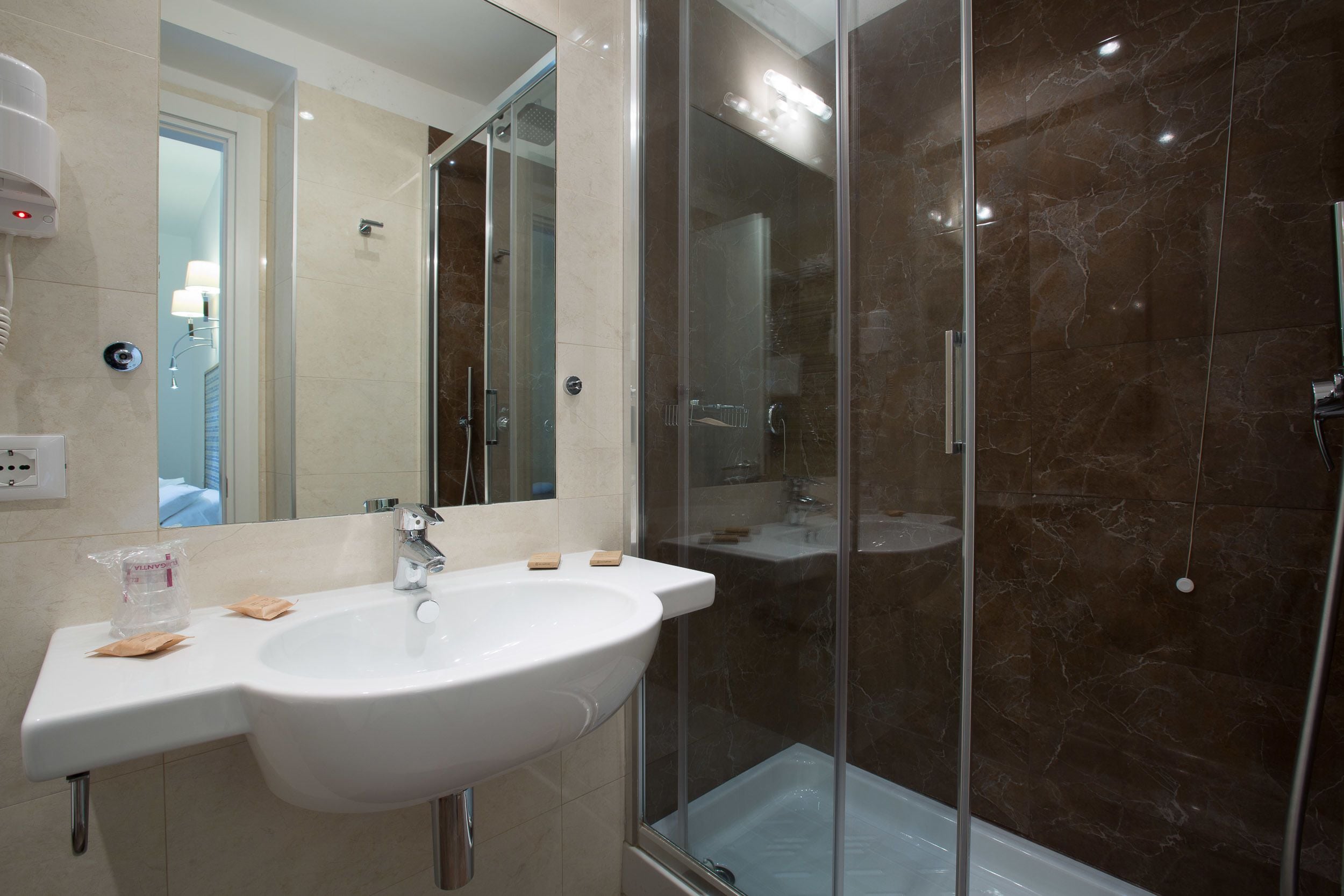 Une salle de bain moderne avec un grand lavabo, une douche en verre et un miroir.
