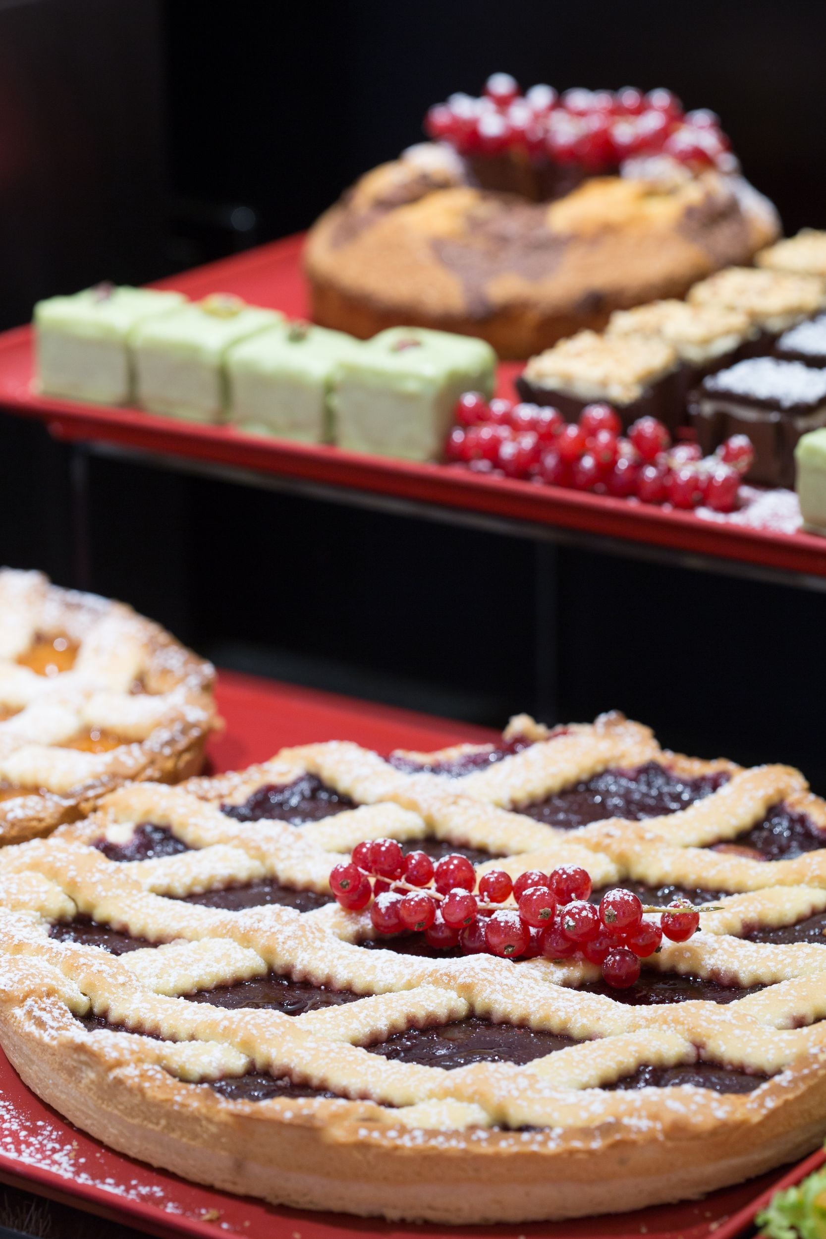 Une variété de desserts est présentée sur la table, notamment une tarte aux cerises et d’autres pâtisseries.